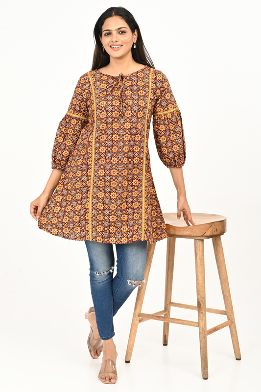Woman wearing rust yellow all-over print 100% cotton tunic top paired with blue jeans
