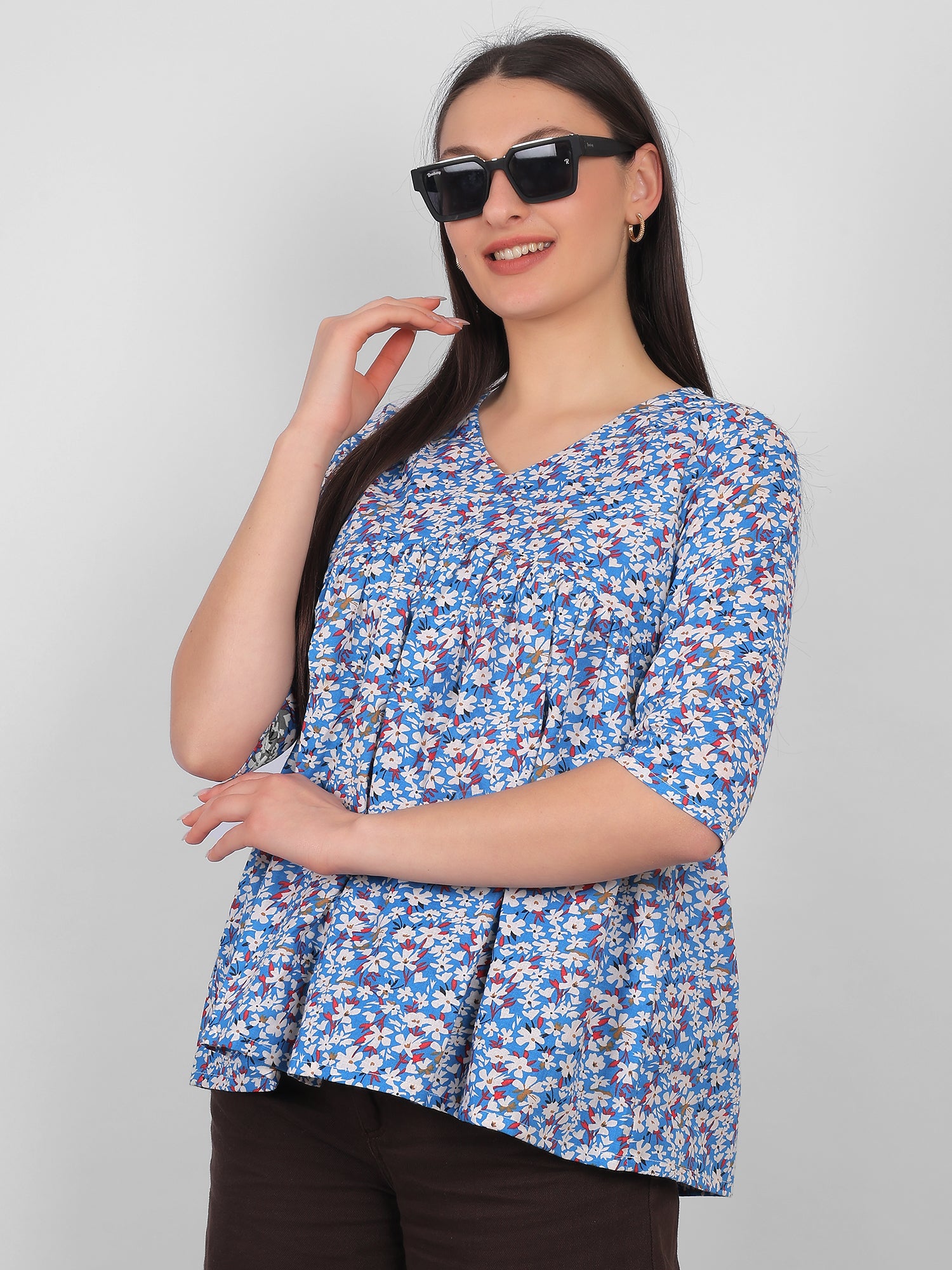 Side pose of woman wearing blue floral printed 100% cotton top for women with V neck and three quarter sleeves, summer wear in India