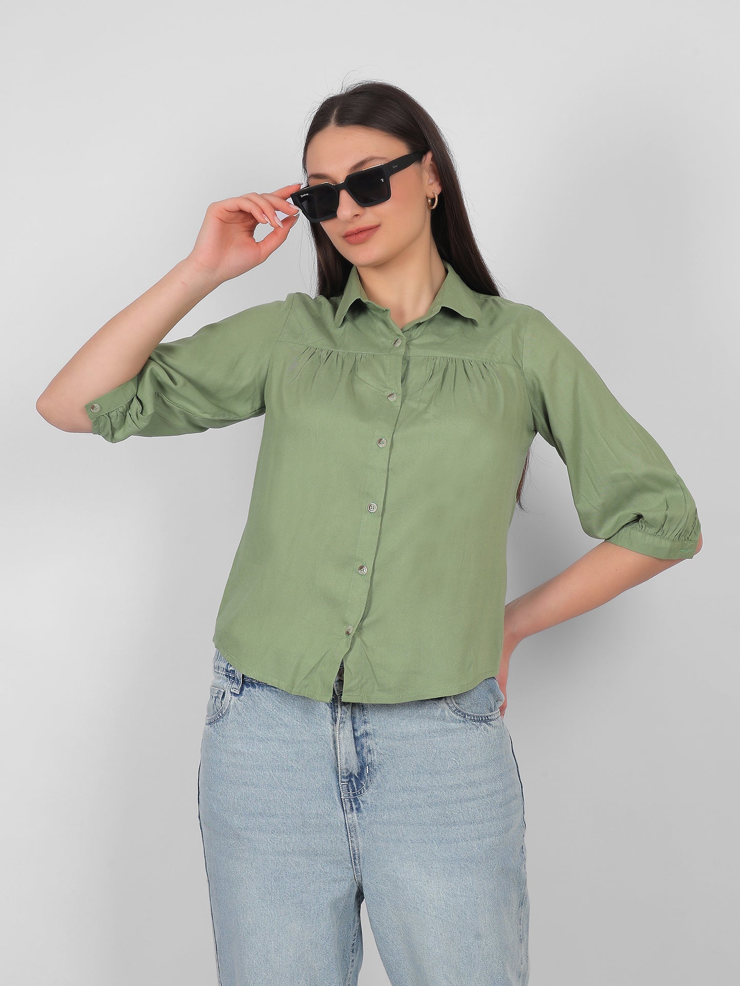 Solid green 100% rayon top for women styled with sunglasses, front view showing collared neckline, front buttons and three quarter sleeves, trendy casual wear top for Indian women