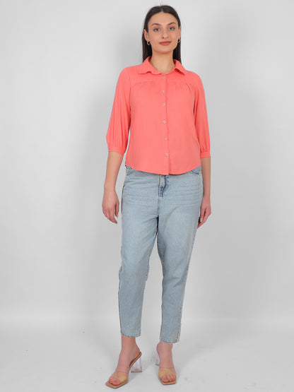 Solid coral pink 100% rayon top for women styled with jeans, full length front view showing collared neckline, front button design and three quarter sleeves, casual and office wear outfit for Indian women