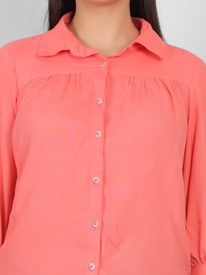 Close up view of solid coral pink 100% rayon top for women showing collared neckline, front button placket and gathered yoke detail, premium casual and office wear top for Indian women