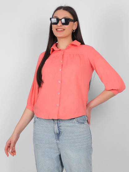 Solid coral pink 100% rayon top for women styled with sunglasses, front view showing collared neckline, front buttons and three quarter sleeves, trendy casual wear top for Indian women