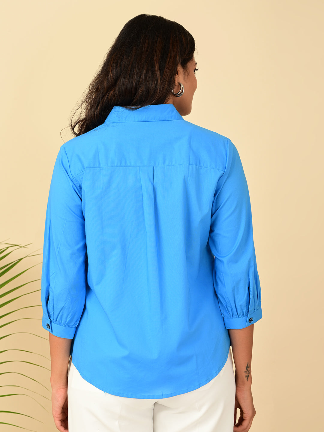 Back view of women's blue cotton shirt with 3/4 puff sleeves and button cuffs