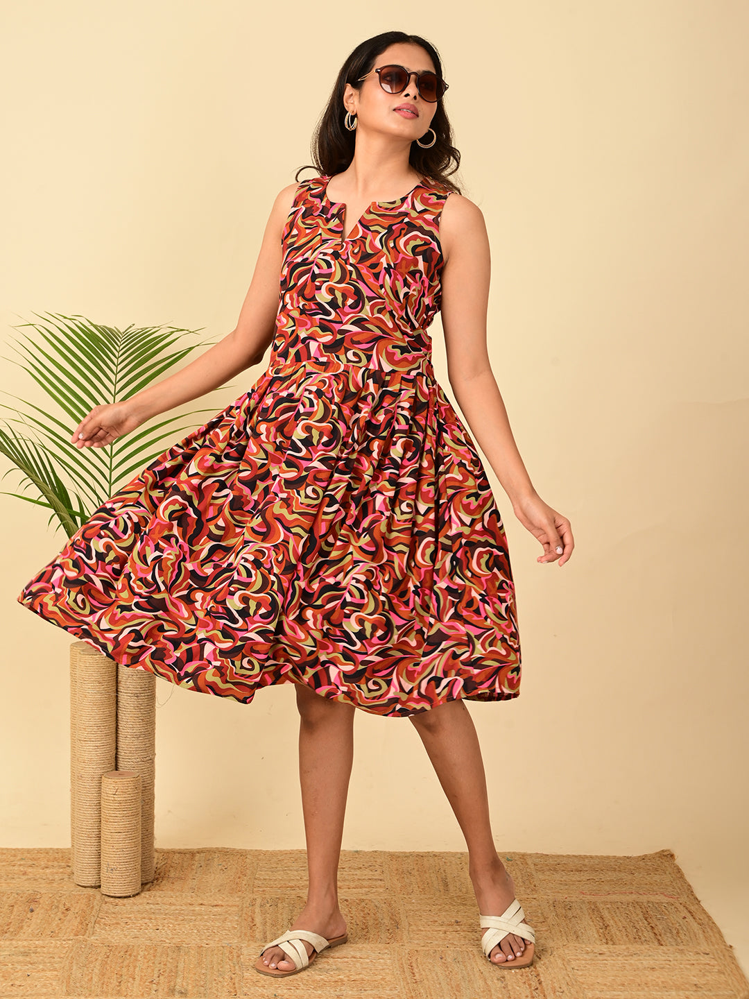 Woman wearing a multicolor all-over printed rayon midi dress for women in India with sleeveless design, fit and flare silhouette, soft breathable fabric, and flowing twirl look.