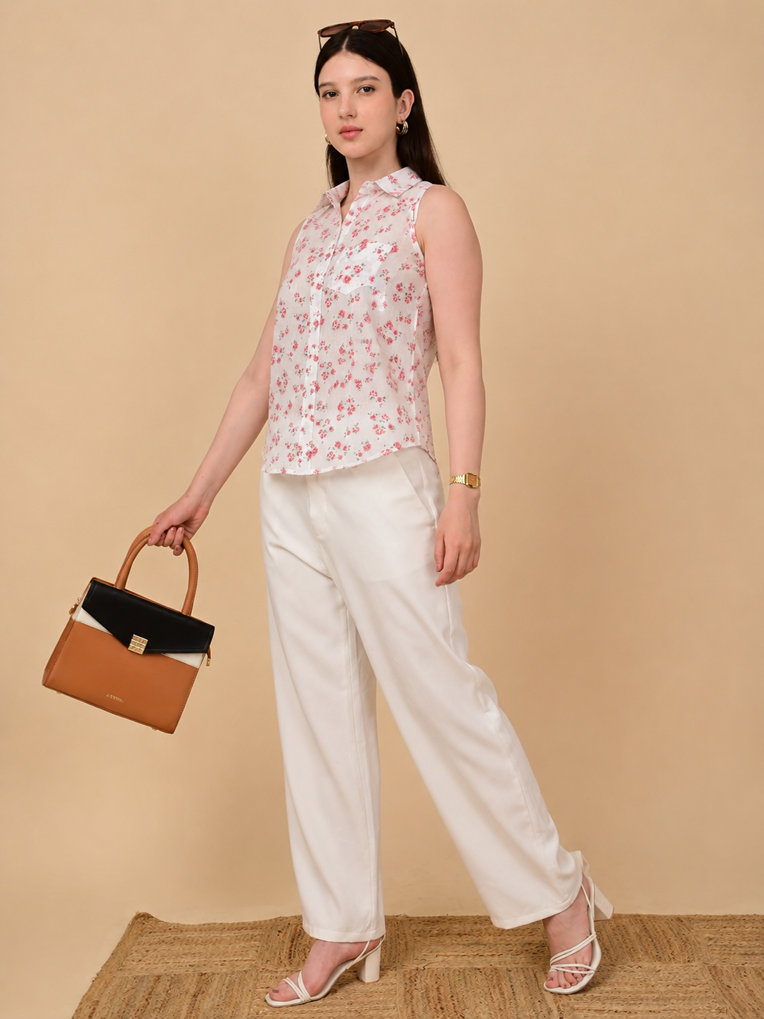 White floral sleeveless shirt for women styled with white trousers and handbag